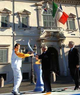 Il Presidente Ciampi consegna la Torcia olimpica al 1° tedoforo Stefano Baldini. A destra nella foto, Valentino Castellani, Presidente del Comitato Organizzatore Olimpico Torino 2006