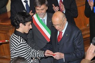 Il Presidente Giorgio Napolitano consegna una copia della Costituzione a uno studente in occasione della Giornata Nazionale della Bandiera.
